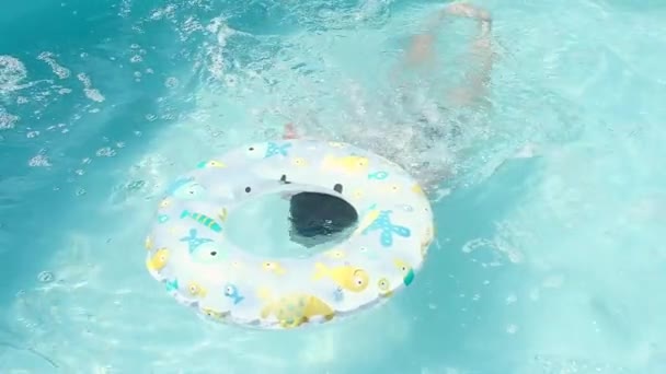 少年はプールに飛び込み、水の下で泳ぎ、浮き上がり、膨脹可能な円の中で頭を打つ。暑い夏の日にホームフレームプールで泳ぐ。スローモーション、ハードライト. - 映像、動画