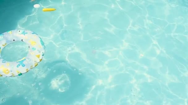 Der Junge taucht mit Spielzeug und einem aufblasbaren Kreis aus dem Wasser und schwimmt unter Wasser. die Aussicht von oben. Schwimmen im heimischen Pool an einem heißen Sommertag. Zeitlupe, hartes Licht. - Filmmaterial, Video