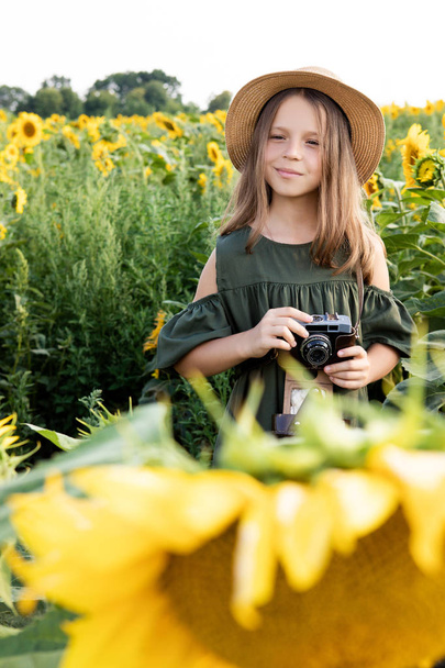 Uma blogueira de girassóis. Com um chapéu e um lindo vestido. Com uma câmera vintage
. - Foto, Imagem