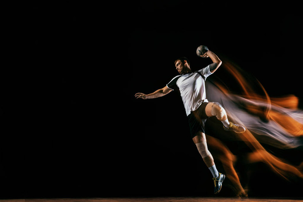 Młody gracz piłki ręcznej przeciwko ciemnym tle studyjnej w mieszanym świetle - Zdjęcie, obraz