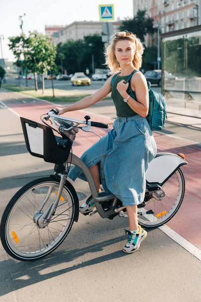 Photo of young girl sitting on bicycle near bus stop - Fotografie, Obrázek