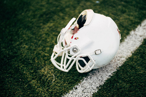Photo of white helmet of Amerinian football player on green lawn - Zdjęcie, obraz