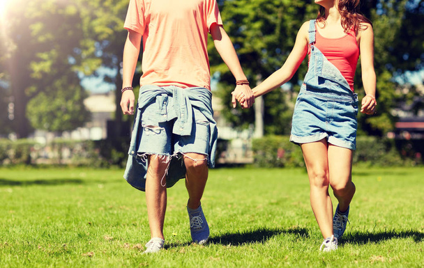 happy teenage couple walking at summer park - 写真・画像