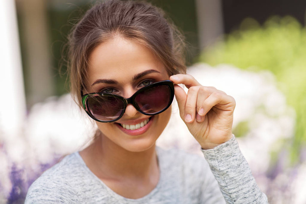 happy young woman in sunglasses at summer garden - 写真・画像