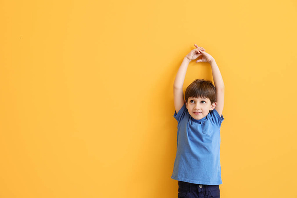 Cute little boy measuring height near color wall - Photo, image
