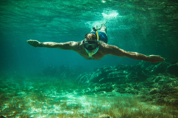 Junger Mann erkundet Meeresboden beim Tauchen im blauen Meer - Foto, Bild