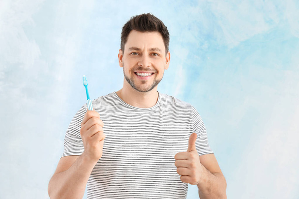 Man with toothbrush on light background - Фото, изображение
