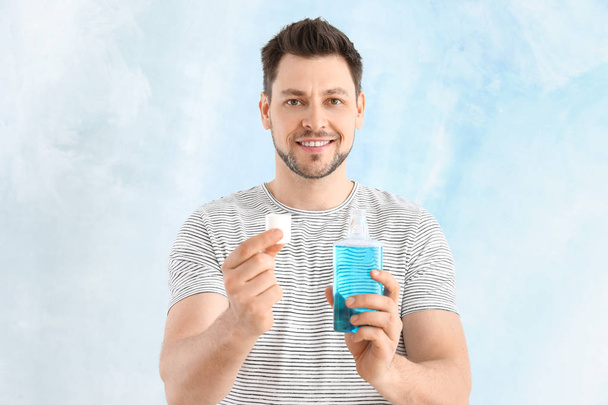 Man with mouth rinse on light background - Photo, Image