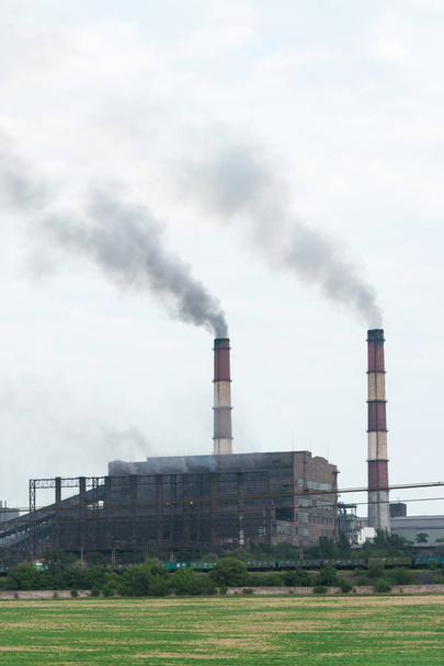 Θέα του εργοστασίου στην πόλη, καπνός από την καμινάδα. Ατμοσφαιρική ρύπανση, υπερθέρμανση του πλανήτη. - Φωτογραφία, εικόνα