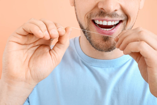 Man flossing teeth on color background, closeup - Photo, Image