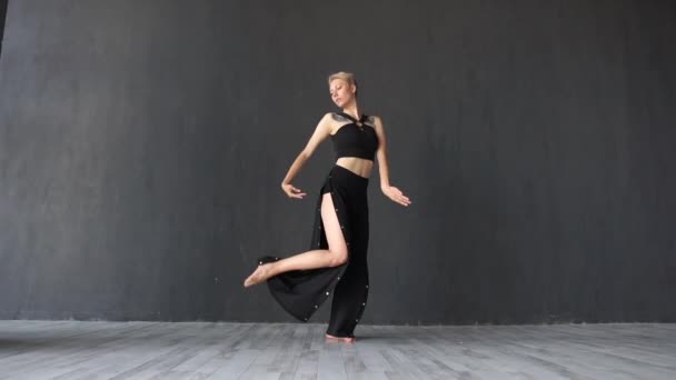 Καλλιτεχνικό ξανθιά κορίτσι γυρίζοντας γύρω και κουνώντας τα πόδια της στο στούντιο σε αργή-mo - Πλάνα, βίντεο