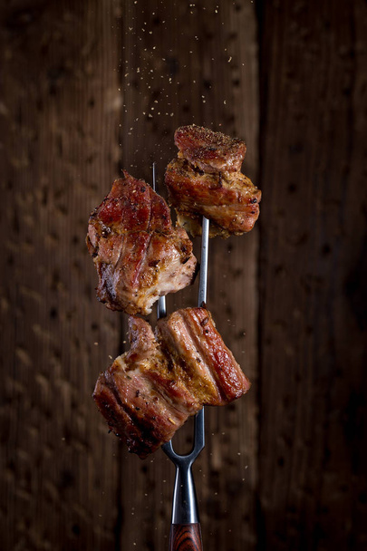Carving fork with pieces of steak on rustic background - Photo, Image