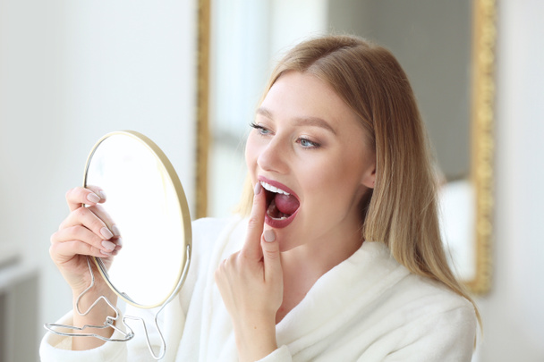 Woman checking whiteness of her teeth at home - Foto, Imagen