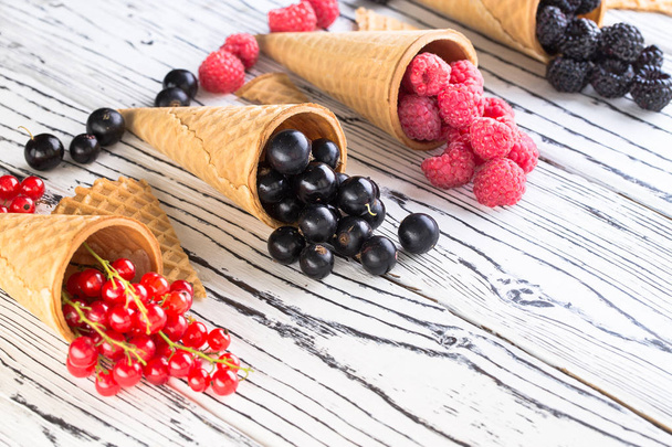 Summer berries in waffle cone on wooden table - Photo, image