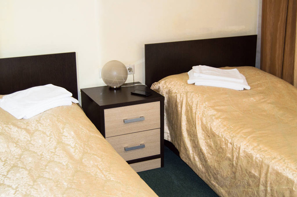Moderna habitación doble con dos camas individuales, mesita de noche, toallas y lámpara de mesa, acogedora habitación económica para los viajeros, buen servicio y hospitalidad del hotelero
 - Foto, Imagen