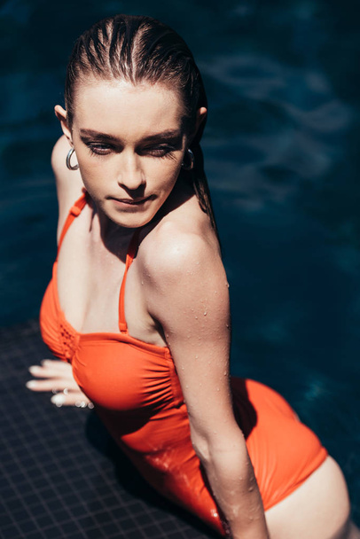 houkutteleva nuori nainen katselee poispäin rentoutuen uima-altaassa
 - Valokuva, kuva