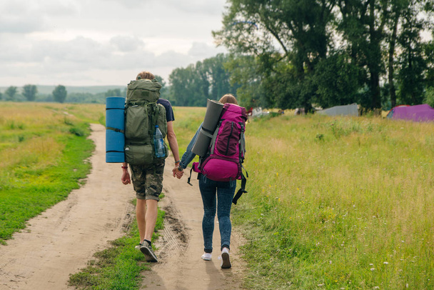 Fashionable love couple with backpacks walk. Tourist girl and ma - Fotó, kép