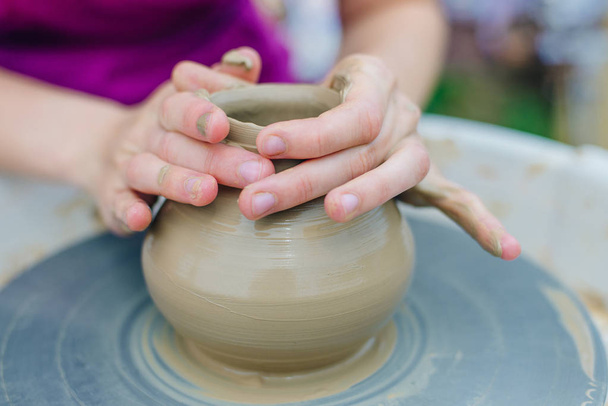 陶工の車輪で働く女性。手はclからコップを彫る - 写真・画像