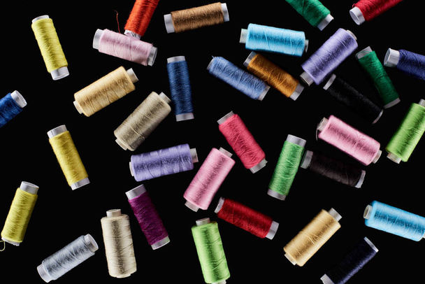 top view of bright and colorful threads isolated on black - Fotó, kép