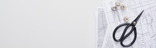 plano panorámico de tijeras, bobinas, dedal y patrones de costura sobre fondo blanco
  - Foto, imagen