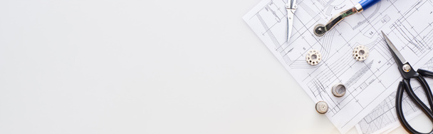 панорамный снимок ножниц, боббинсов, наперстков, роторного резака и узора шитья на белом фоне
  - Фото, изображение
