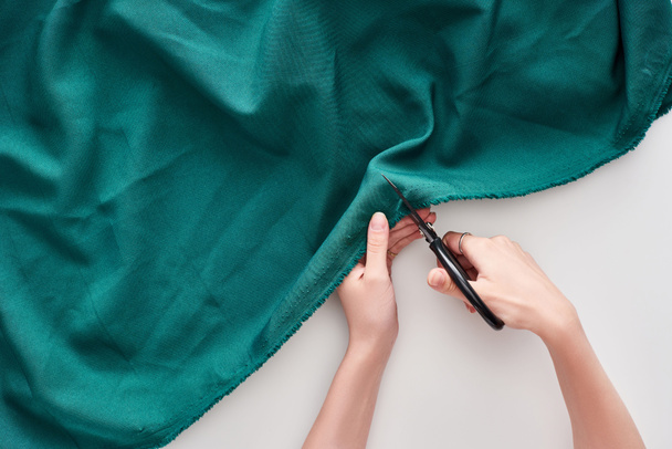 top view of seamstress cutting colorful fabric with scissors on white background  - Foto, afbeelding