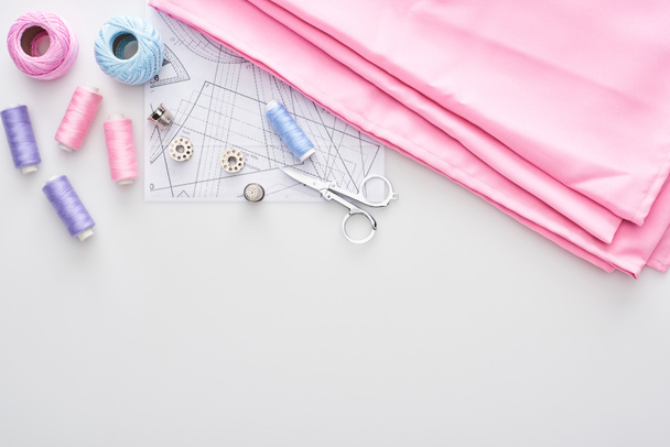 vista superior do tecido, bolas de fio de tricô, padrão de costura, tesoura, dedais, bobinas e fios no fundo branco
  - Foto, Imagem