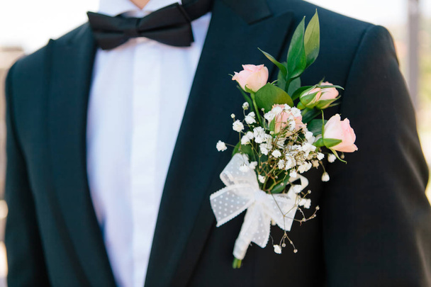 Close-up rosa rosas boutonniere com a decoração em um noivos azul escuro jaqueta elegante, foco seletivo
 - Foto, Imagem