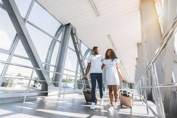 空港でスーツケースを持つアフリカ系アメリカ人カップルの旅行者 - 写真・画像