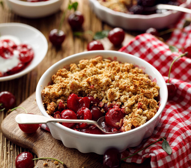 Cherry crumble in a baking dish on a wooden table, close-up - Photo, Image