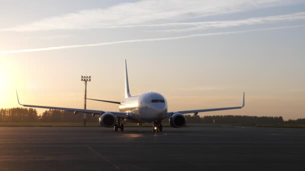 Μεγάλο λευκό αεροπλάνο ετοιμάζεται να πετάξει αρχίζει να κινείται στο διάδρομο το ηλιοβασίλεμα. - Πλάνα, βίντεο
