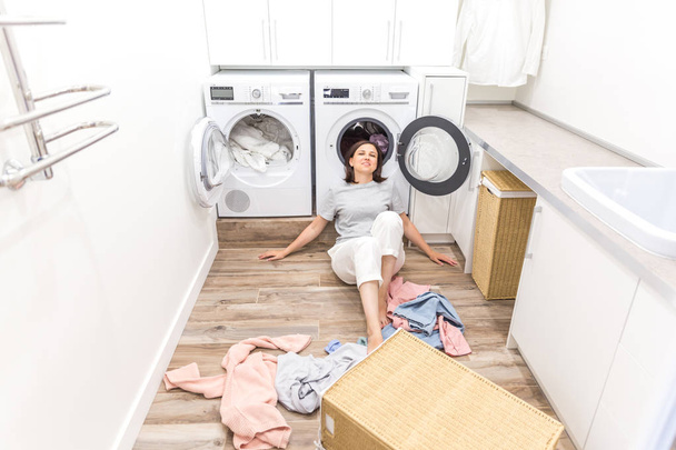 mujer feliz ama de casa en la sala de lavandería cerca de la lavadora con ropa sucia
 - Foto, imagen
