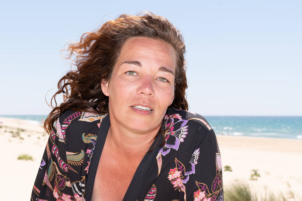 Testa e spalle in vento ritratto di felice bella bruna di mezza età sulla spiaggia
 - Foto, immagini