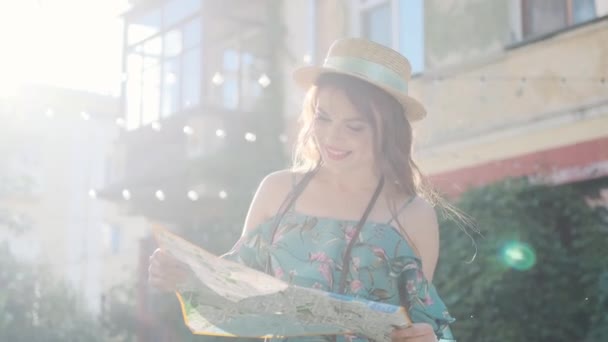 κορίτσι ταξιδιώτης κάθεται στα σκαλιά και κοιτάζει το χάρτη. πορτραίτο μιας νεαρής γυναίκας τουρίστρια - Πλάνα, βίντεο