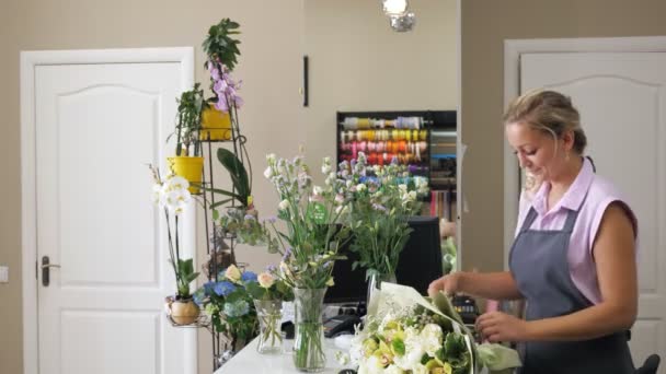 女性花屋のセラーは、花屋で男性の顧客に花束を与えます. - 映像、動画