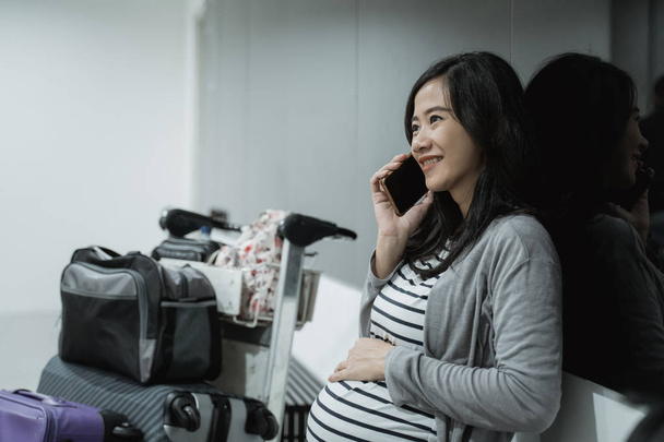 Pregnant woman use cellphones for calling before departure - Photo, image