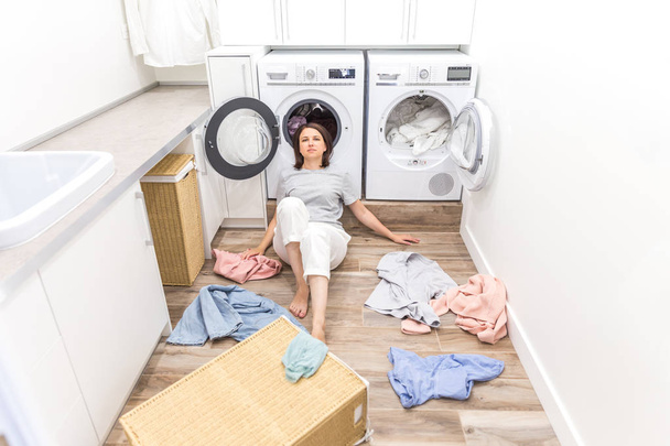 Kobieta szczęśliwa Gospodyni w pralni w pobliżu pralki z brudne ubrania - Zdjęcie, obraz
