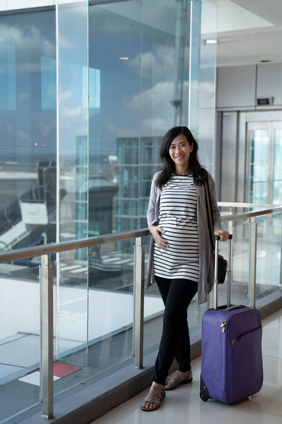 asian pregnant woman standing pulling suitcase - Photo, Image