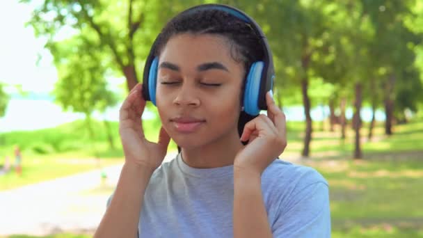 Κλείστε το κορίτσι πρόσωπο με πολύχρωμα πλεξίδες χρησιμοποιώντας ακουστικά - Πλάνα, βίντεο