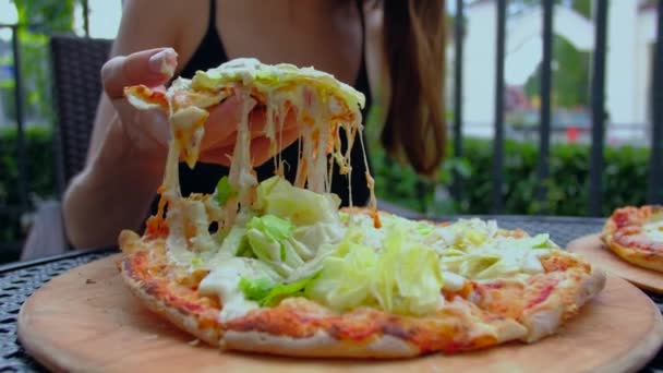 Vrouw neemt smakelijk stukje hete pizza met stretching kaas. - Video