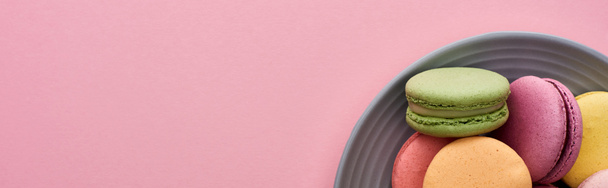 ピンクの背景に多色のおいしいフランスのマカロンとプレートのクローズアップビュー ロイヤリティフリー写真 画像素材