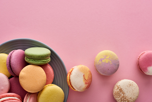 plate with multicolored tasty French macaroons on pink background - Photo, Image