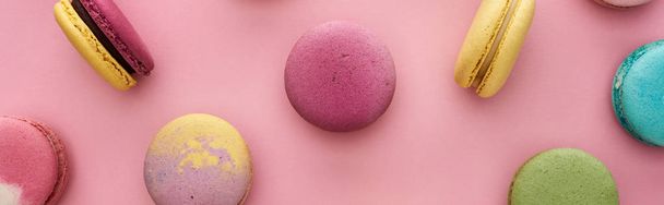 pattern of multicolored delicious French macaroons scattered on pink background, panoramic shot - Valokuva, kuva