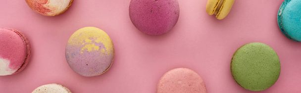pattern of multicolored delicious French macaroons on pink background, panoramic shot - Fotó, kép