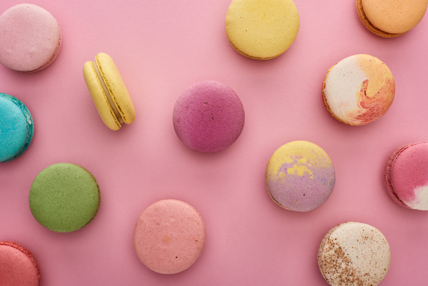 vzorek barevných chutných francouzských macaroonů rozptýlených na růžovém pozadí - Fotografie, Obrázek