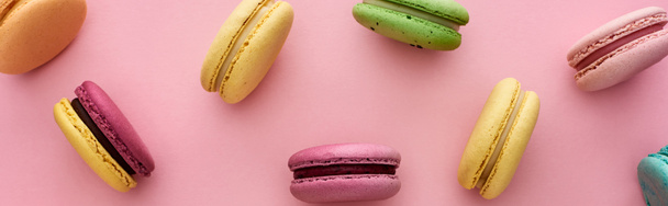 vzorek barevných chutných francouzských macaroonů rozptýlených na růžovém pozadí, panoramatický záběr - Fotografie, Obrázek