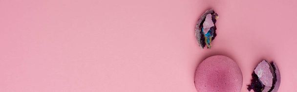 pohled na rozbité a celé lahodné purpurové francouzské makaroony na růžovém pozadí s prostorem pro kopírování, panoramatický záběr - Fotografie, Obrázek