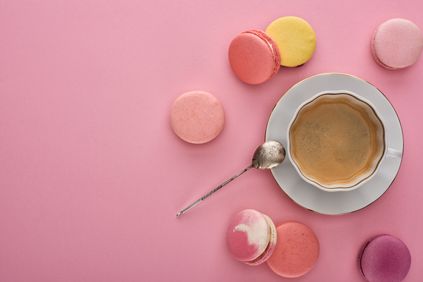top view of delicious French macaroons near coffee on pink background with copy space - 写真・画像
