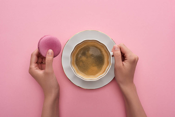 cropped view of woman drinking coffee with delicious French macaroon on pink background - Foto, Bild