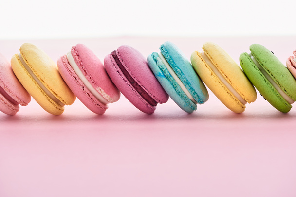 row of delicious colorful French macaroons of different flavors on pink background with copy space - Φωτογραφία, εικόνα